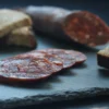 Spanish beef chorizo, whole and sliced, showing its smooth texture and deep red color.